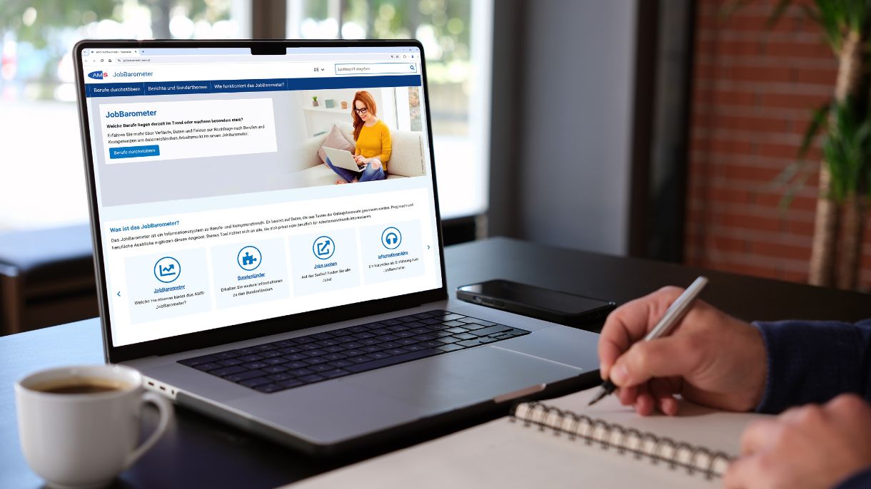 AMS JobBarometer, @AMS - iStock.com/shapecharge Person schreibt in Notizbuch und hat AMS Webseite am Laptop offen